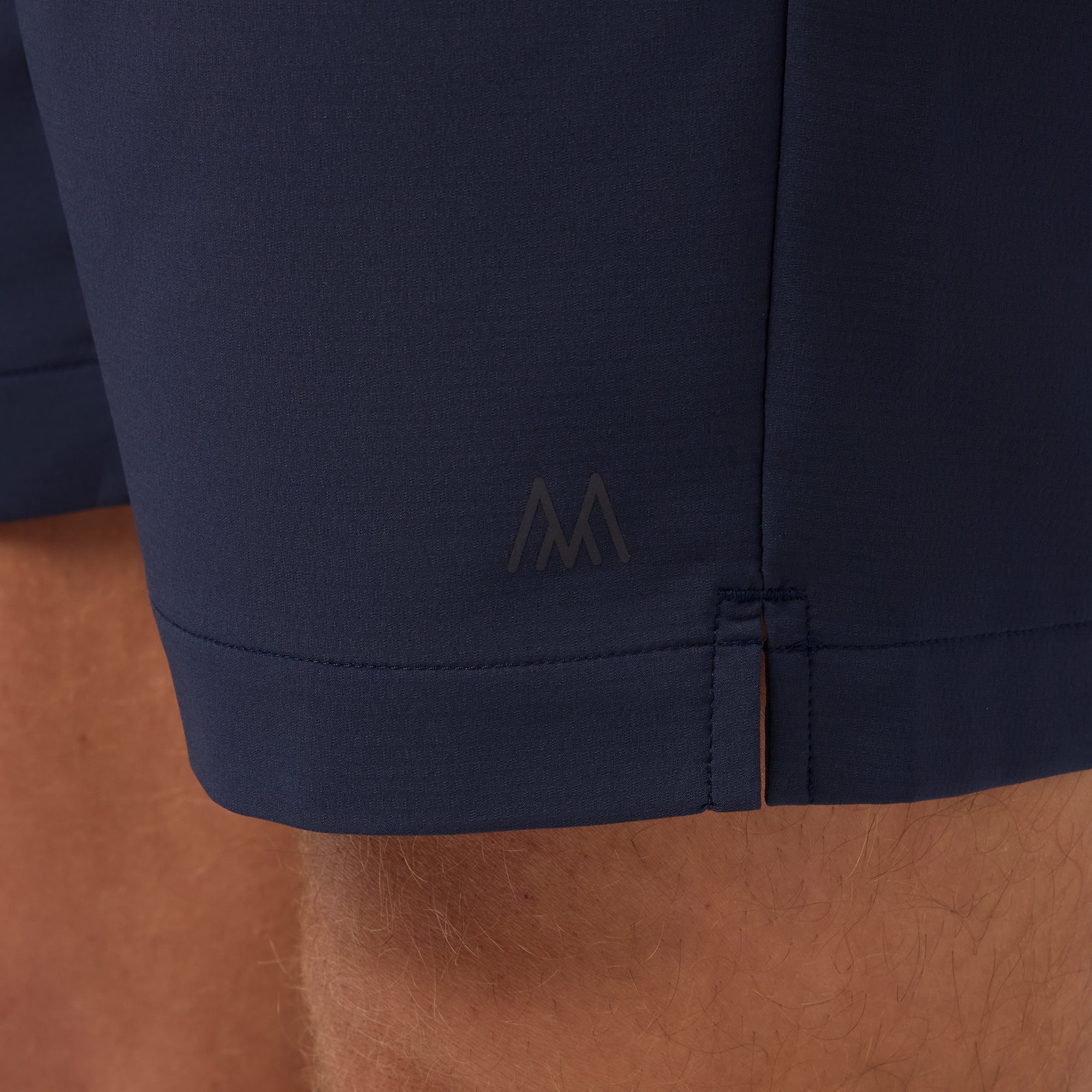 Navy blue pants with a logo on the cuff against a brown background