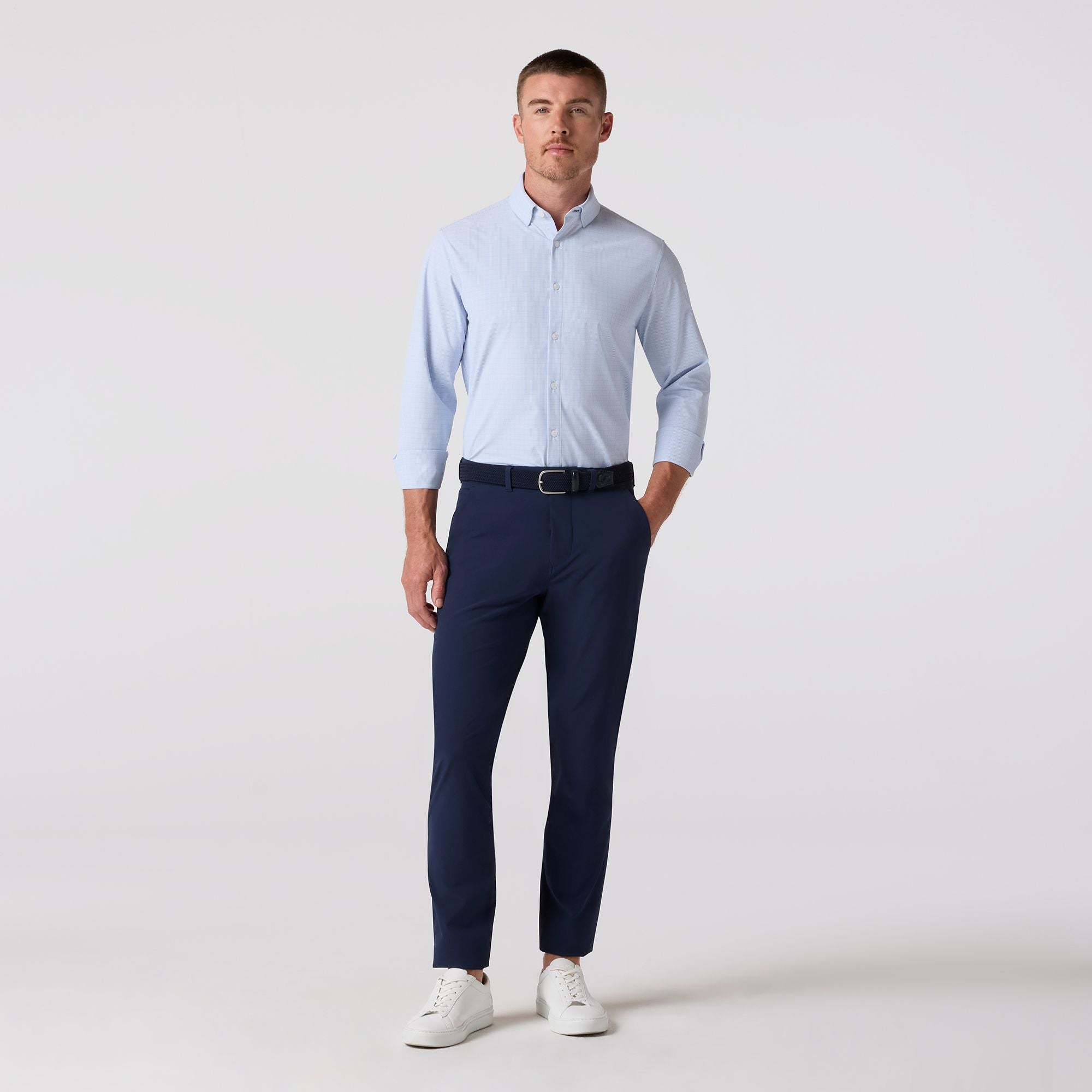 Man wearing a light blue shirt and navy pants on a white background