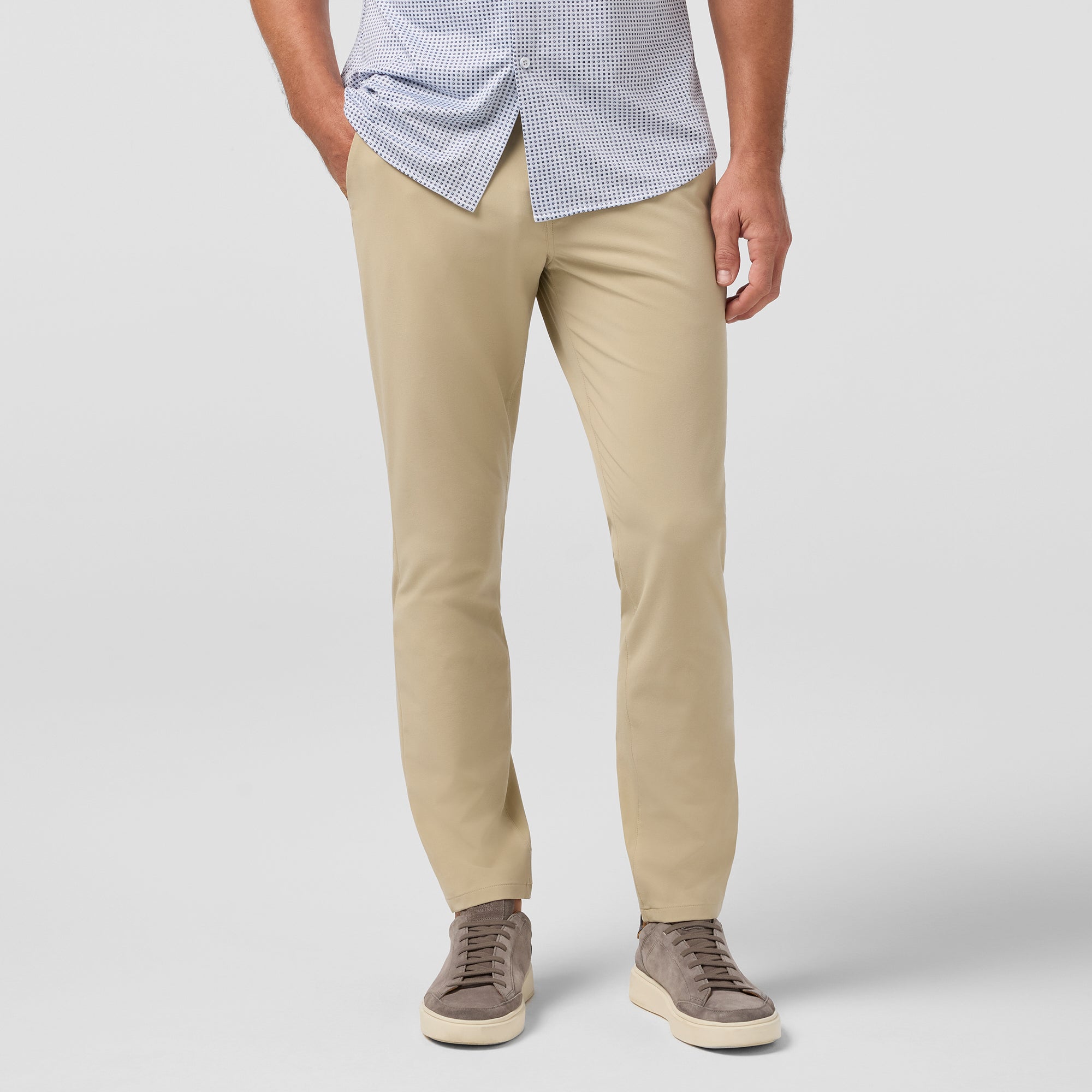 Person wearing beige pants and a checkered shirt on a plain background