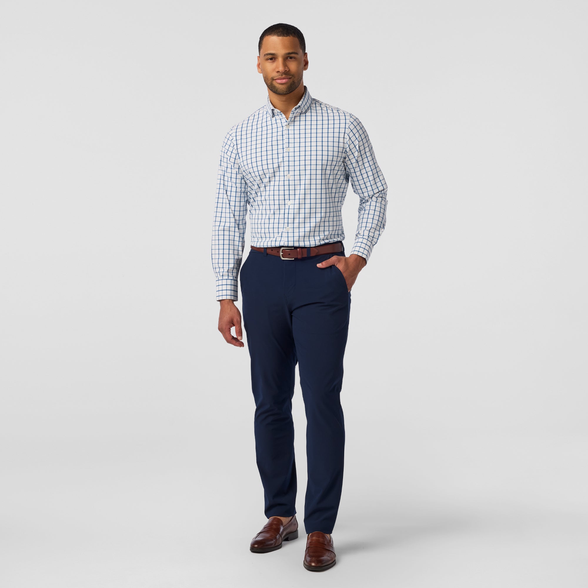 Man wearing a checkered shirt, navy pants, and brown shoes on a white background