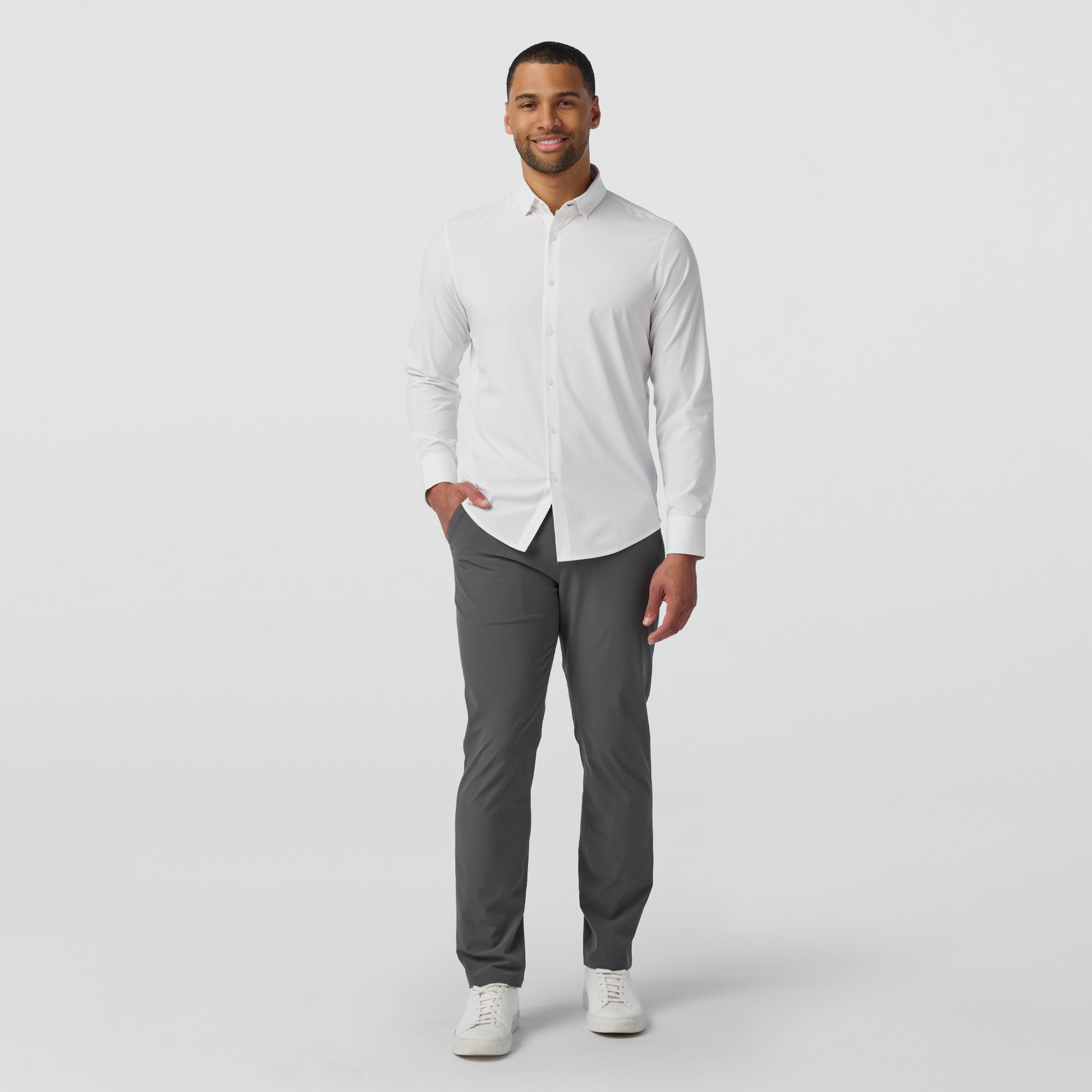 Man wearing a white dress shirt and gray pants on a light gray background