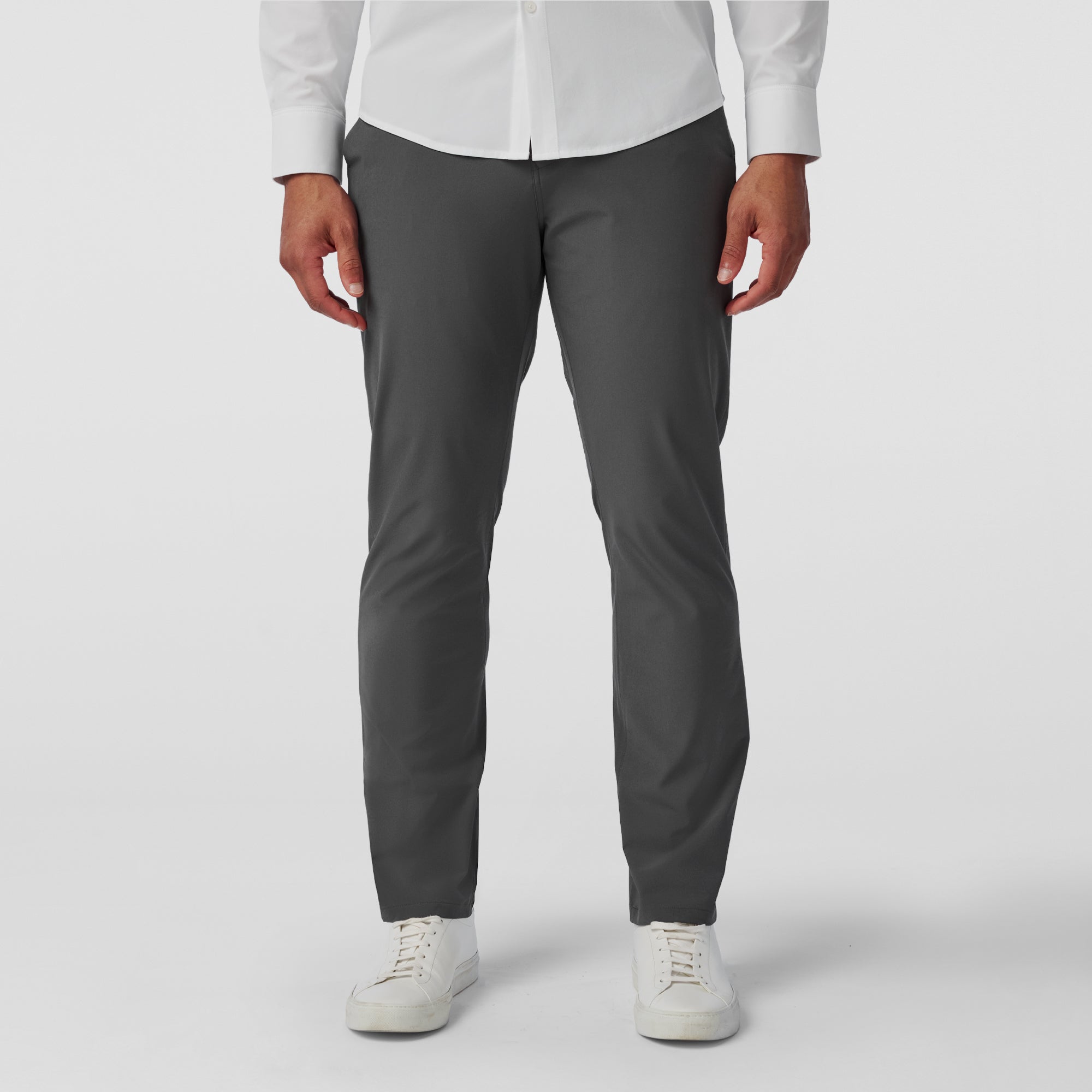 Person wearing gray pants and a white shirt on a plain background