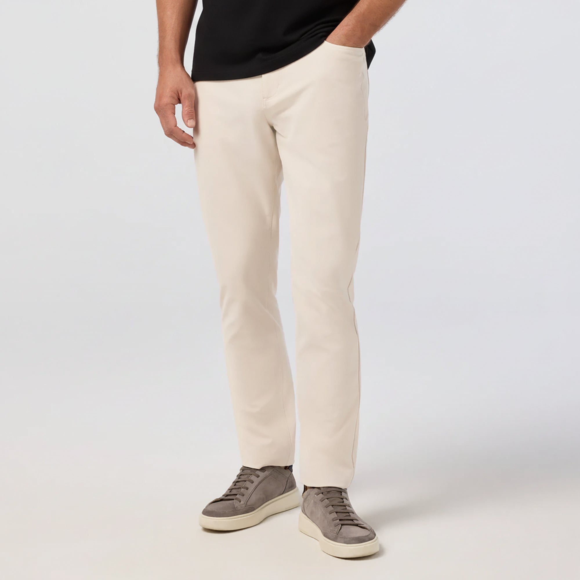 Person wearing beige pants and brown shoes on a white background