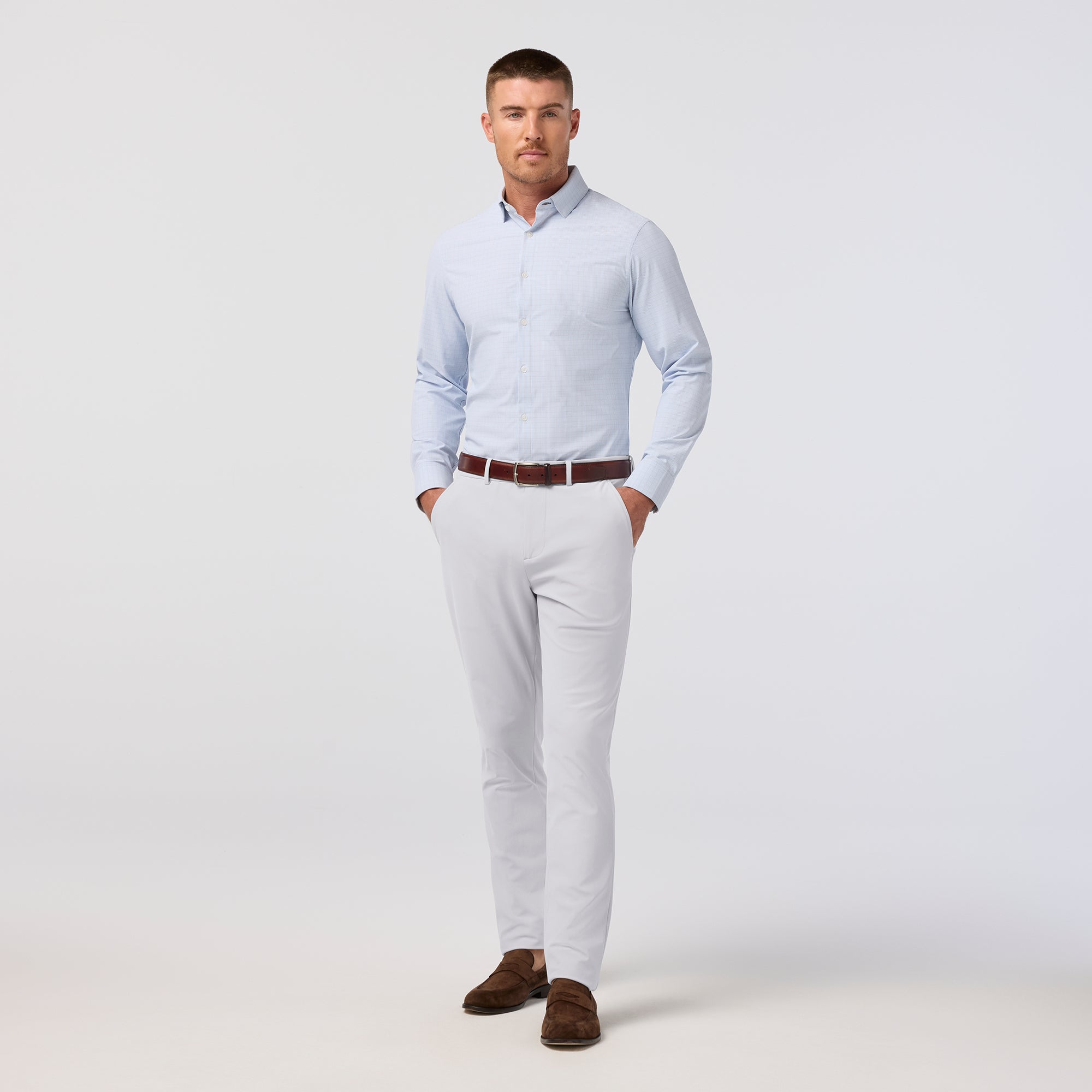 Man wearing a light blue shirt, white pants, and brown shoes on a white background