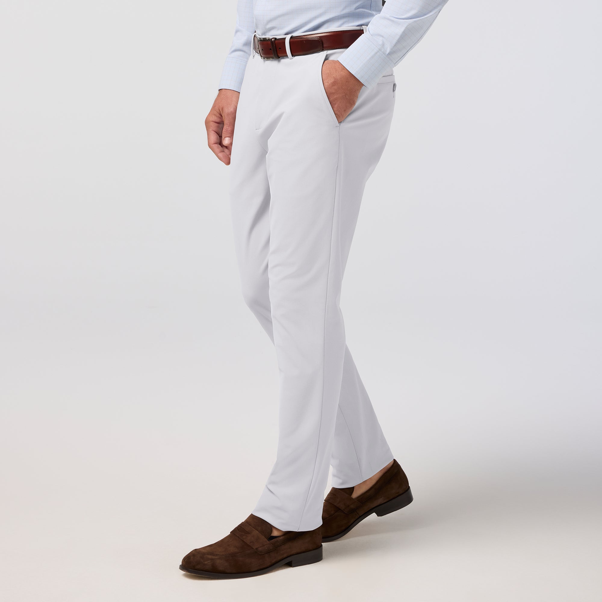 Person wearing white pants and brown shoes on a light gray background