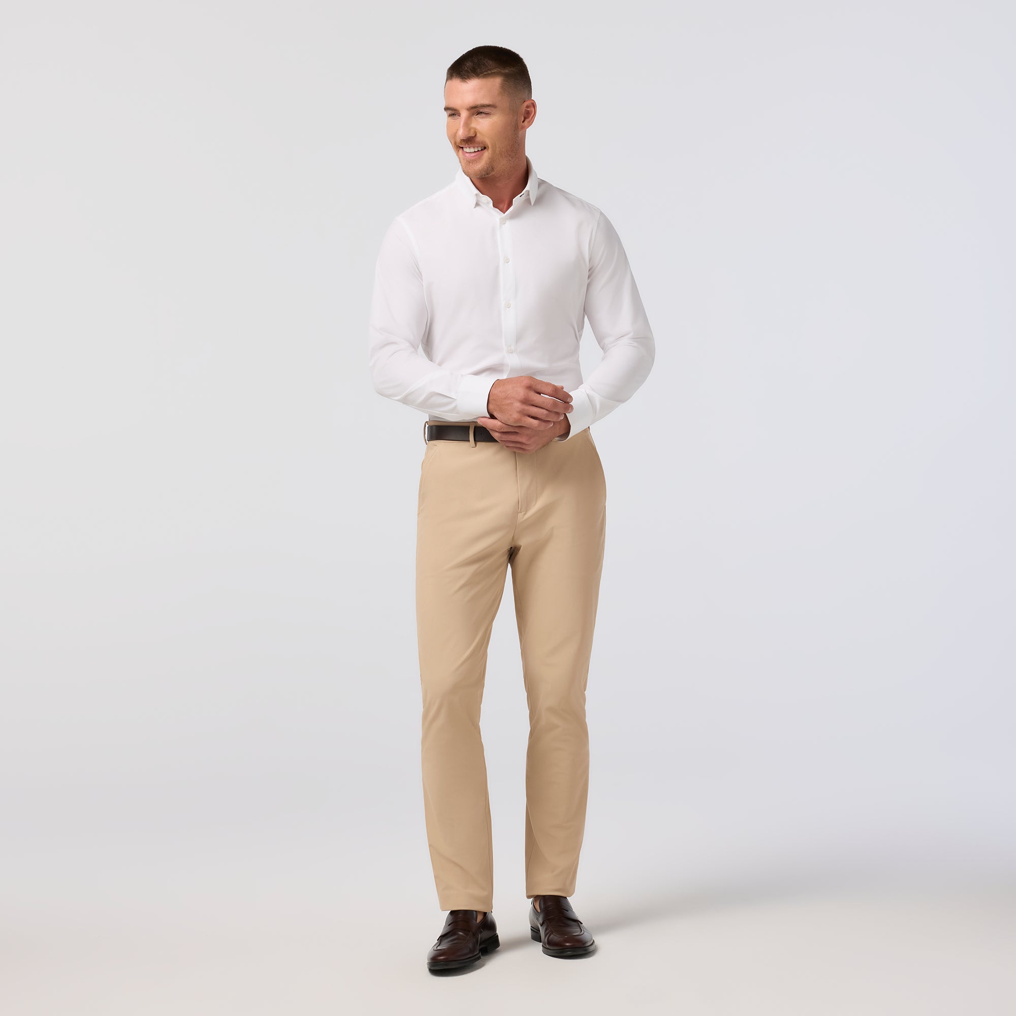Man wearing a white shirt and beige pants on a light gray background