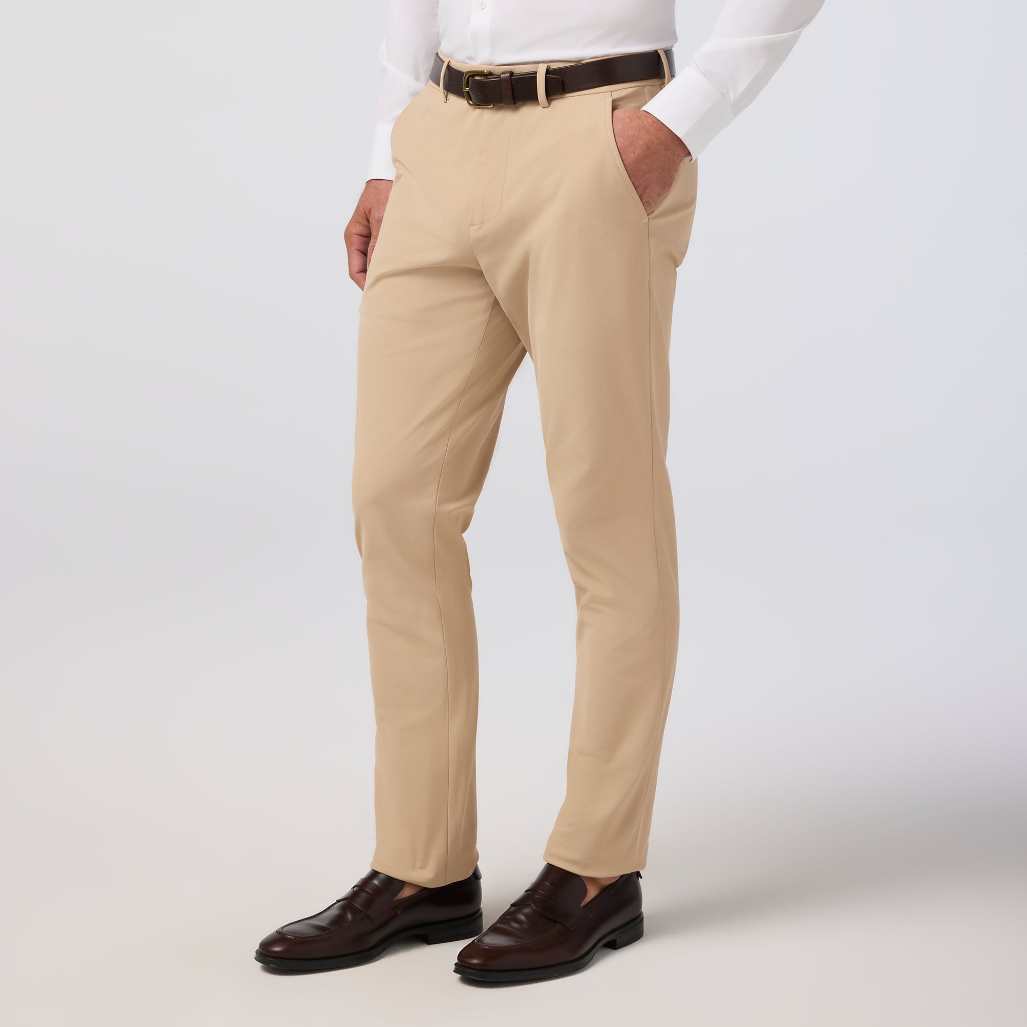 Beige pants worn with a white shirt and brown shoes on a light gray background