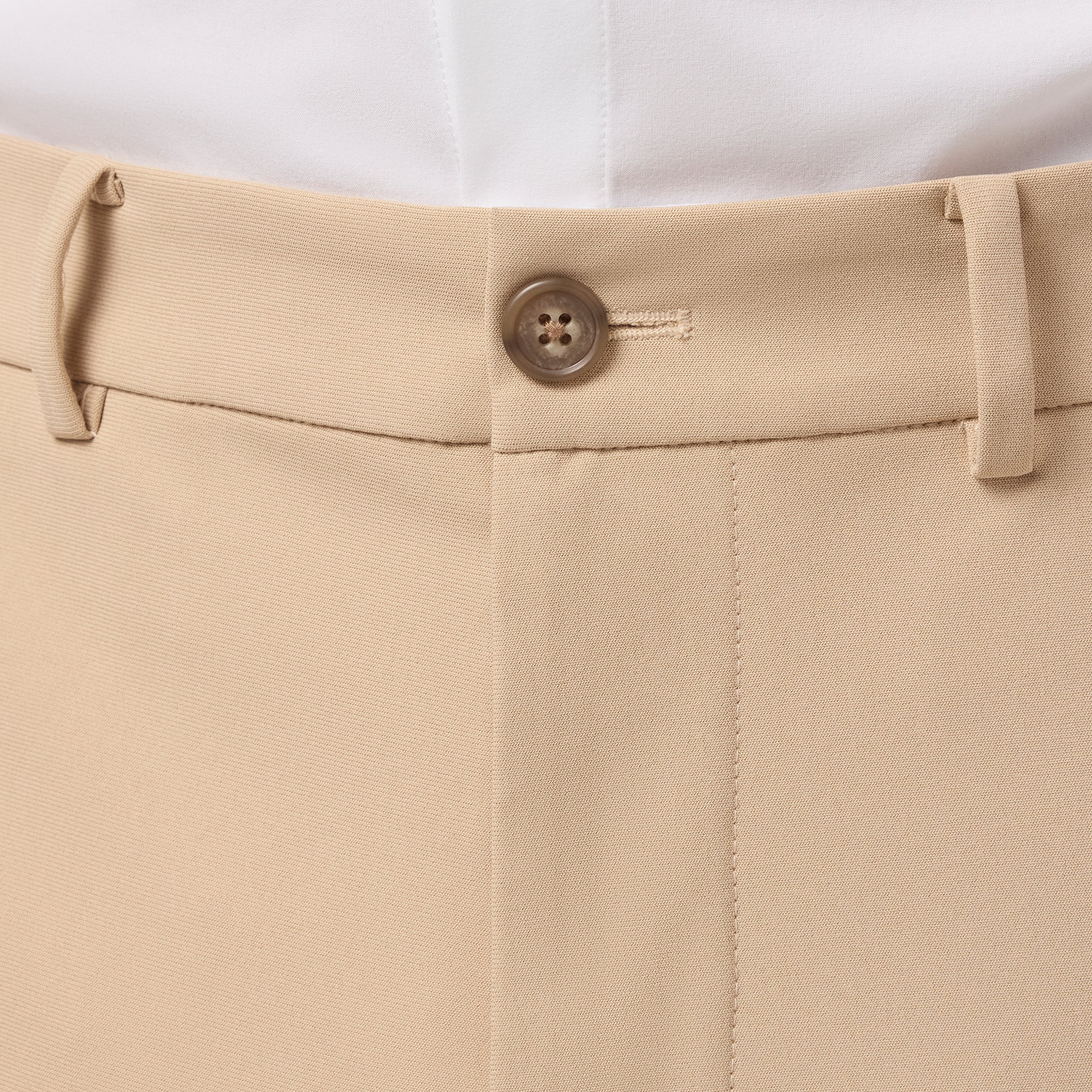 Close-up of beige pants with a button on a white background