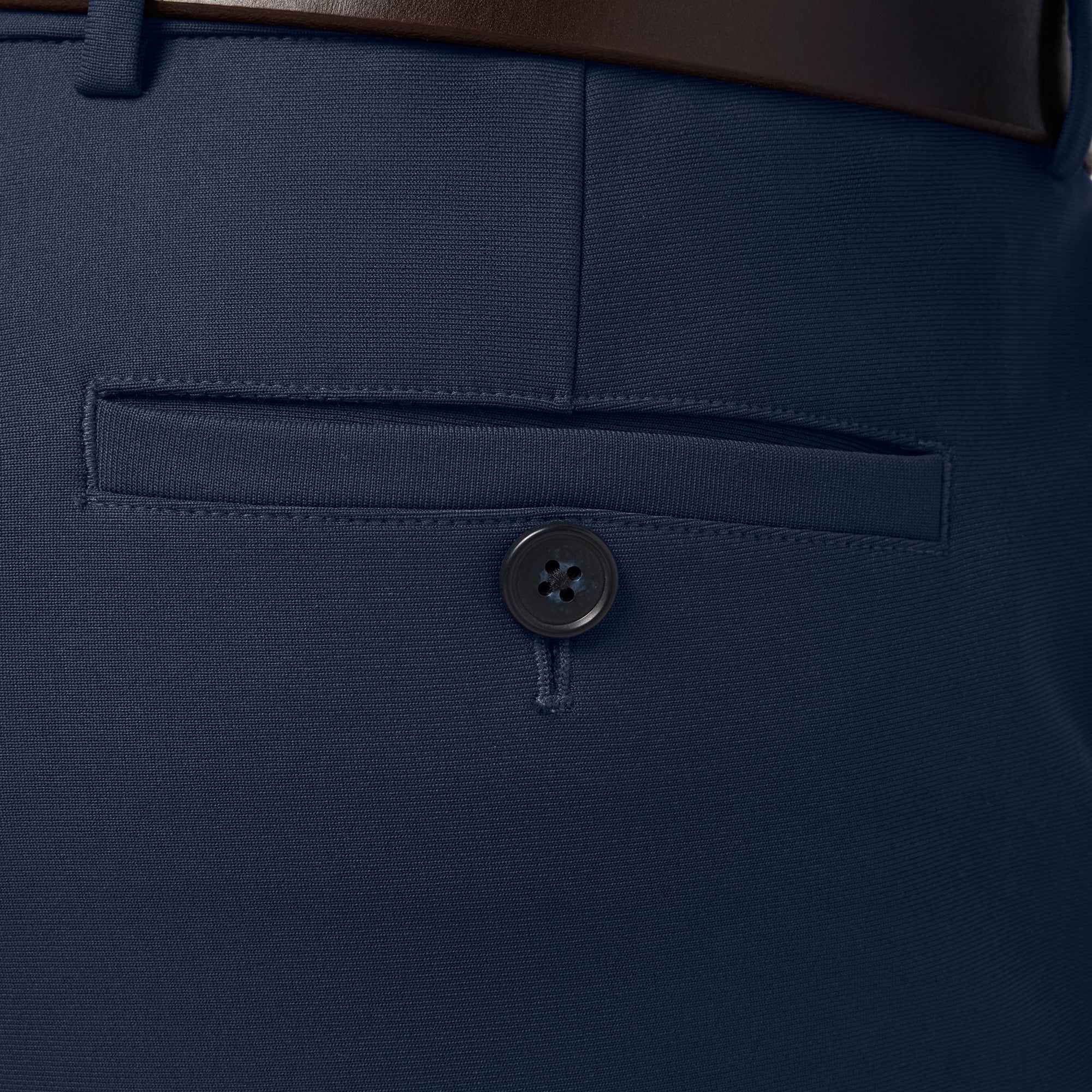 Close-up of a navy blue pocket with a button on a suit jacket.
