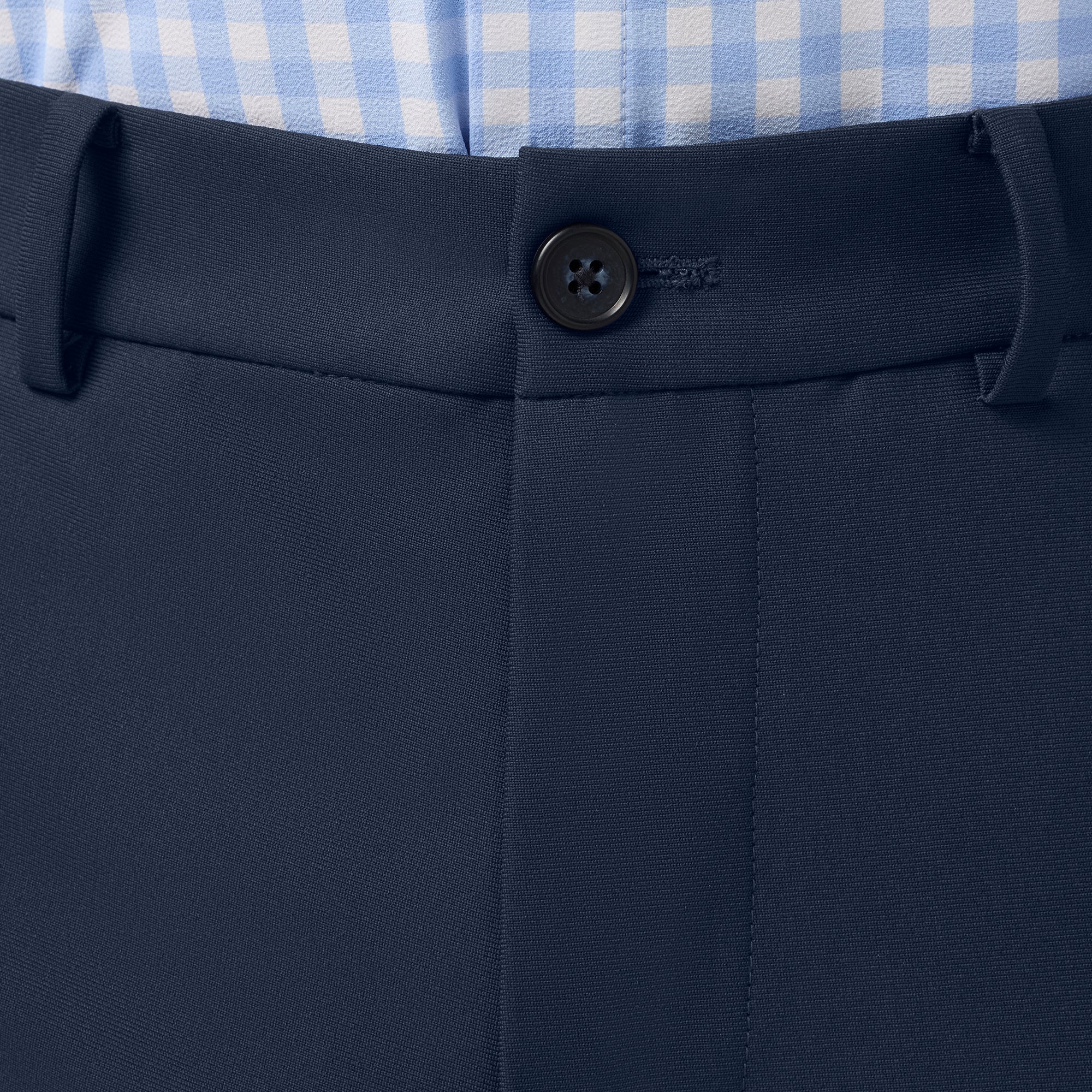 Close-up of navy pants with a button, featuring a brand logo.