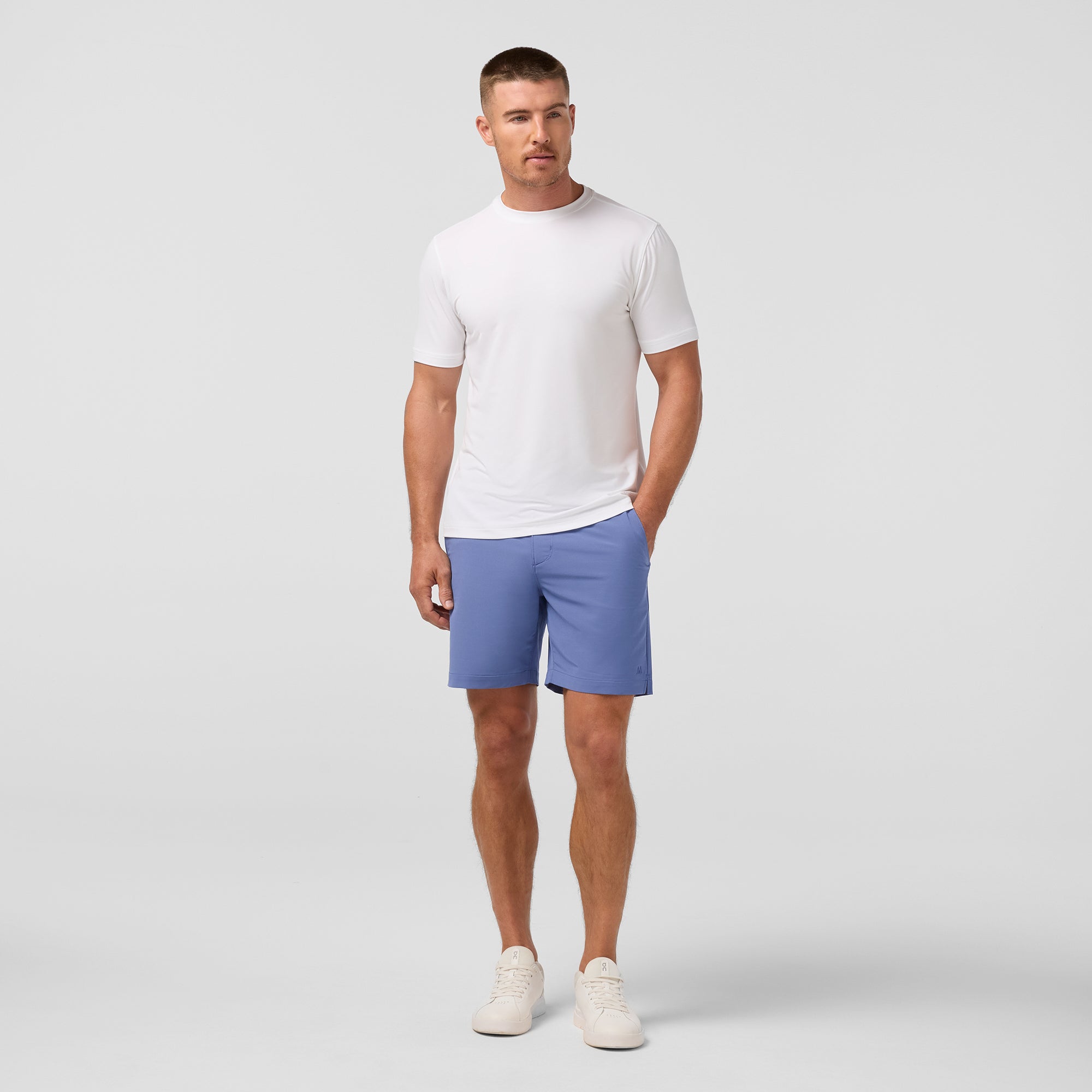 Man wearing a white t-shirt and blue shorts on a light gray background