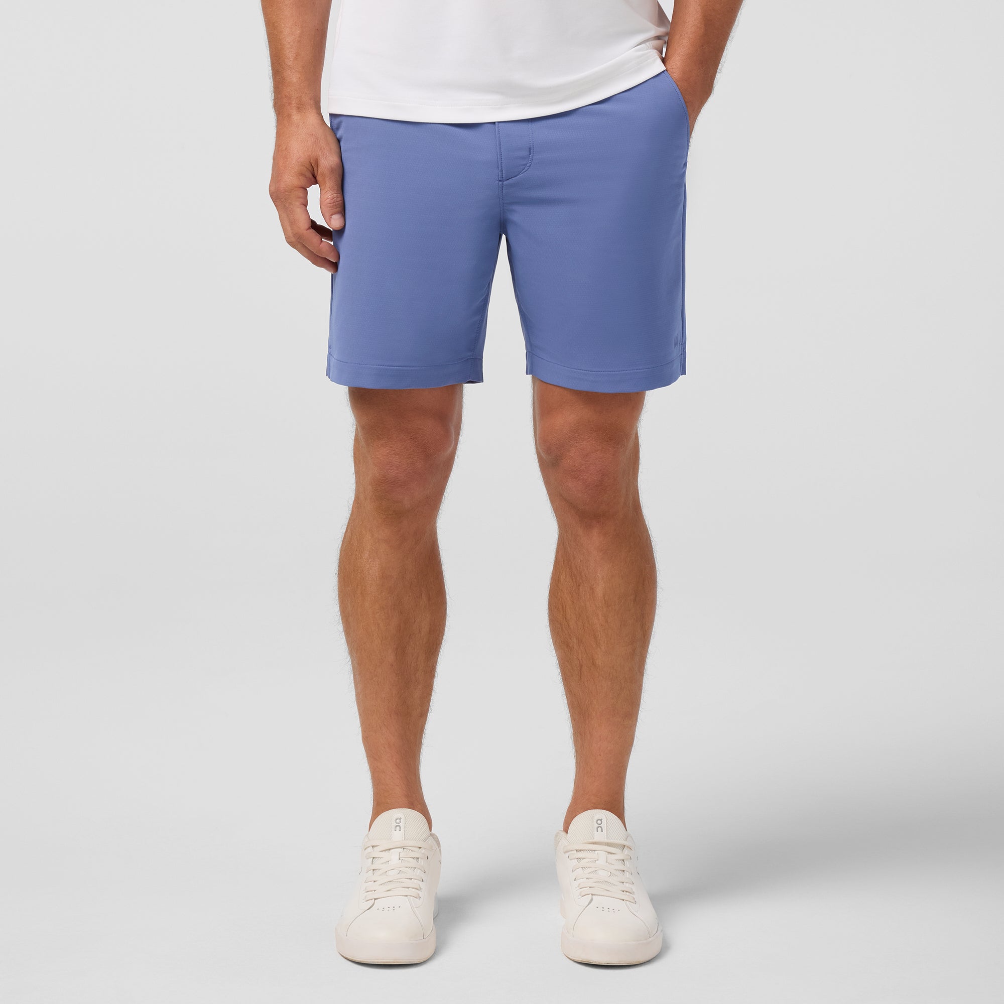Person wearing blue shorts and white sneakers on a plain background