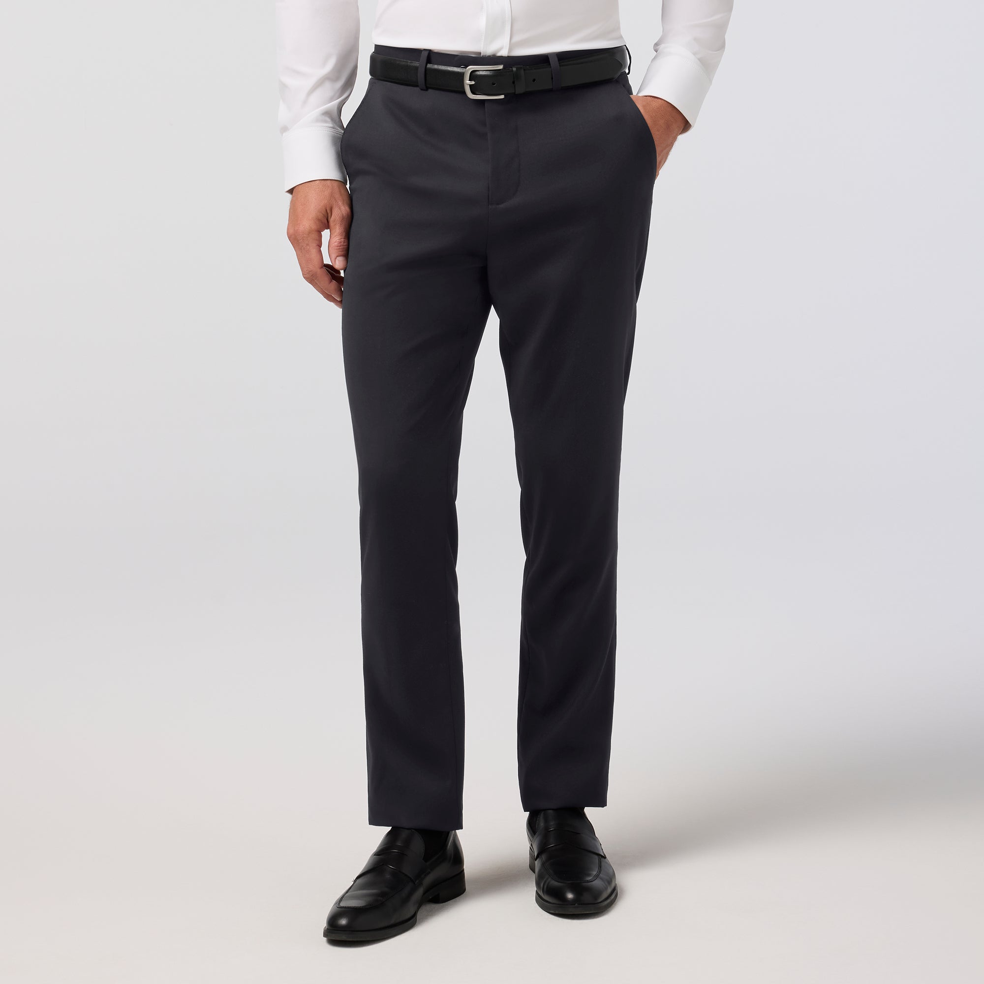 Person wearing black dress pants with a white shirt on a light gray background
