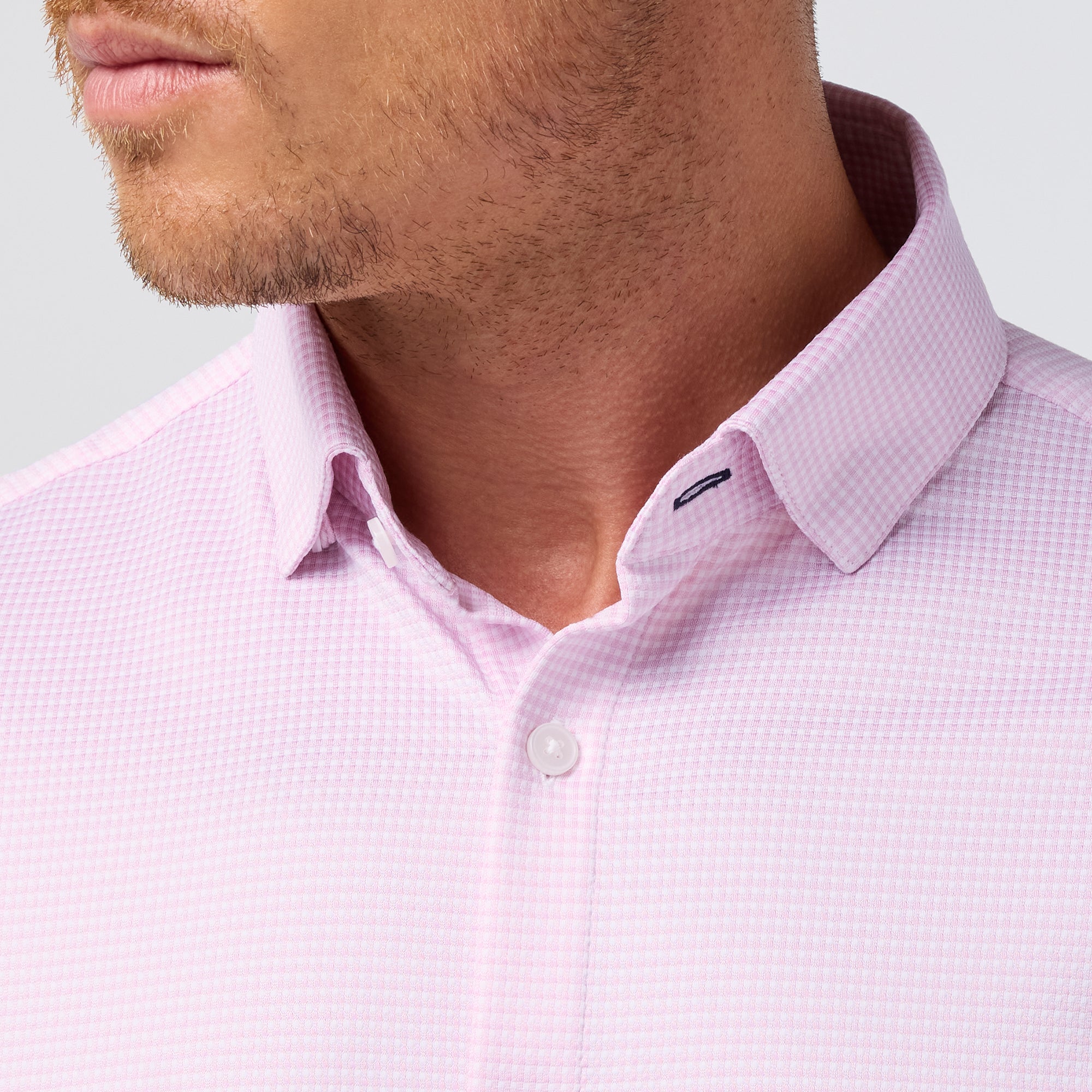Close-up of a man wearing a light pink textured shirt with a collar detail.