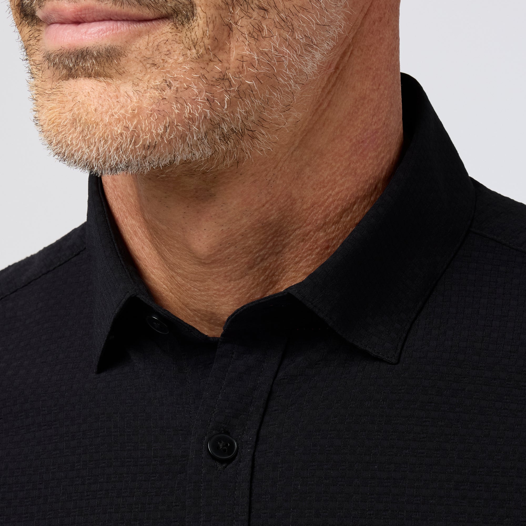Close-up of a man wearing a black shirt against a gray background