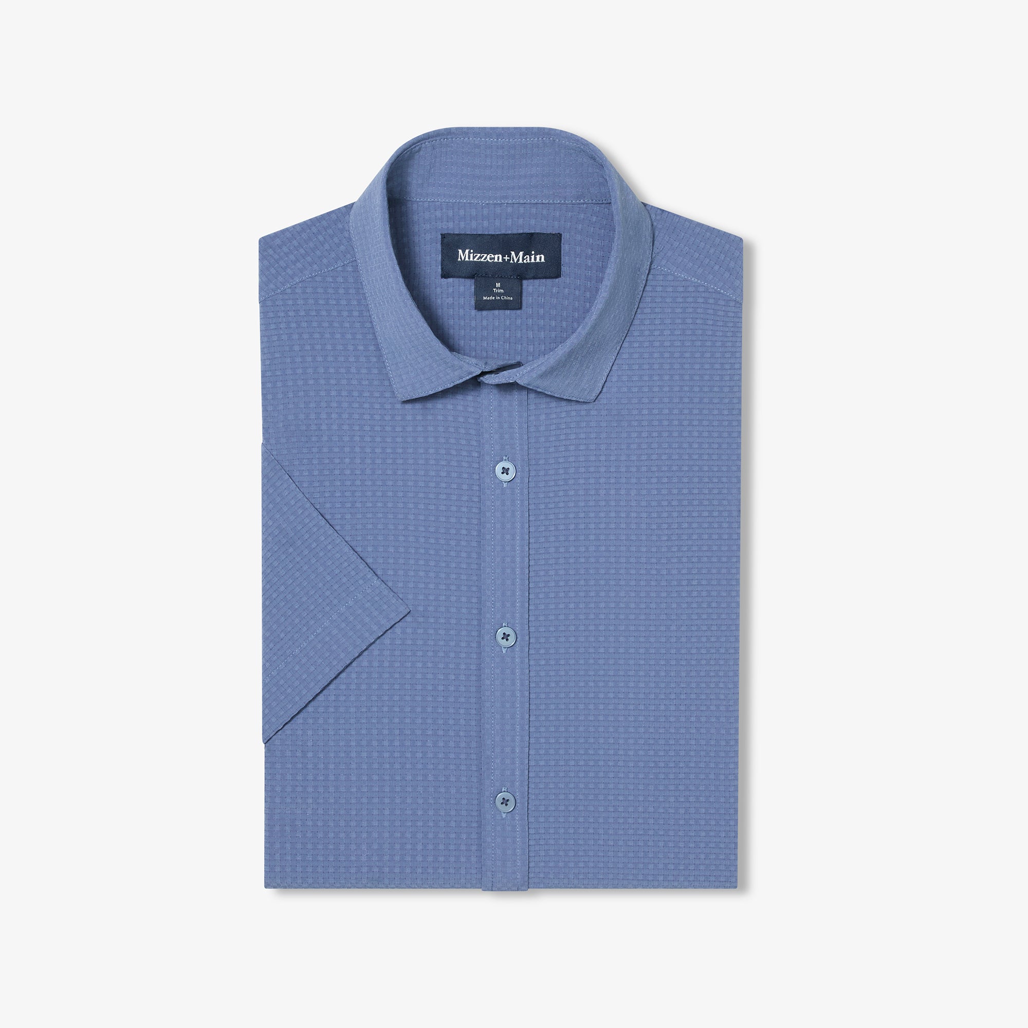 Folded blue textured shirt with a Mizzen+Main label on a light gray background