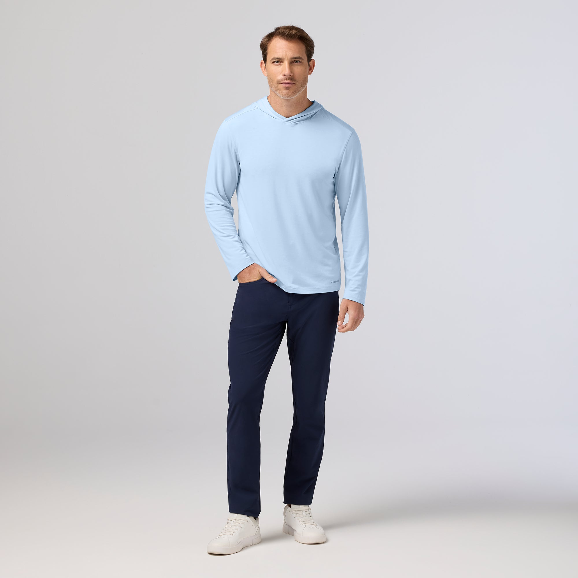 Man wearing a light blue long-sleeve shirt and dark blue pants on a white background